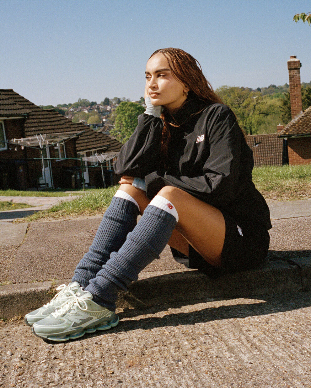 Female HTT sitting on the sidewalk with the sport legacy jacket on.